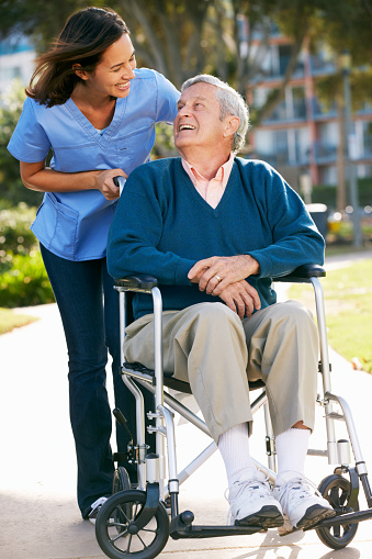 A man in a Wheelchair With a Woman Looking Over