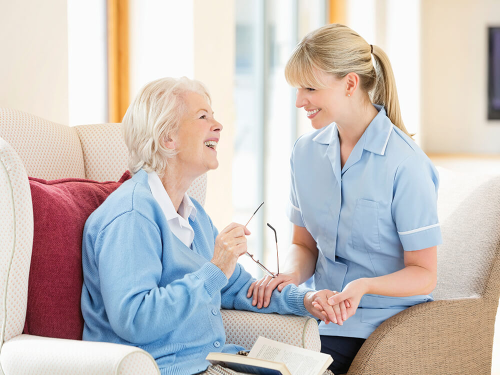 A Helper Smiling and Holding an Elderly Woman Hand